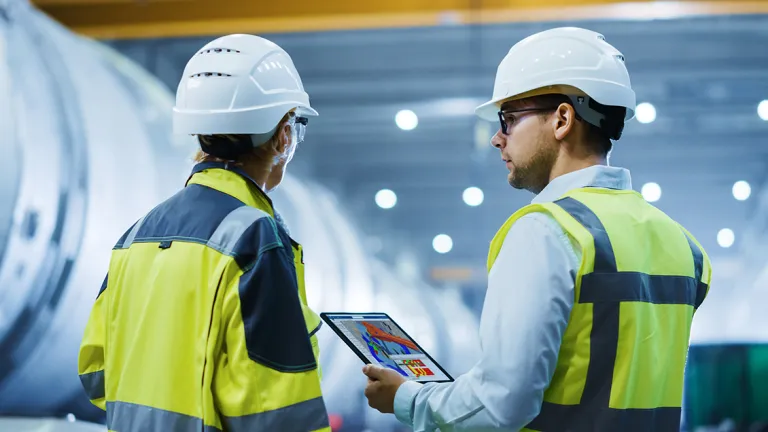 Cloud Solutions for Modular Manufacturing Visibility  > Two Heavy Industry Engineers Stand in Factory With One Engineer Holding Tablet Computer > Dassault Systèmes®